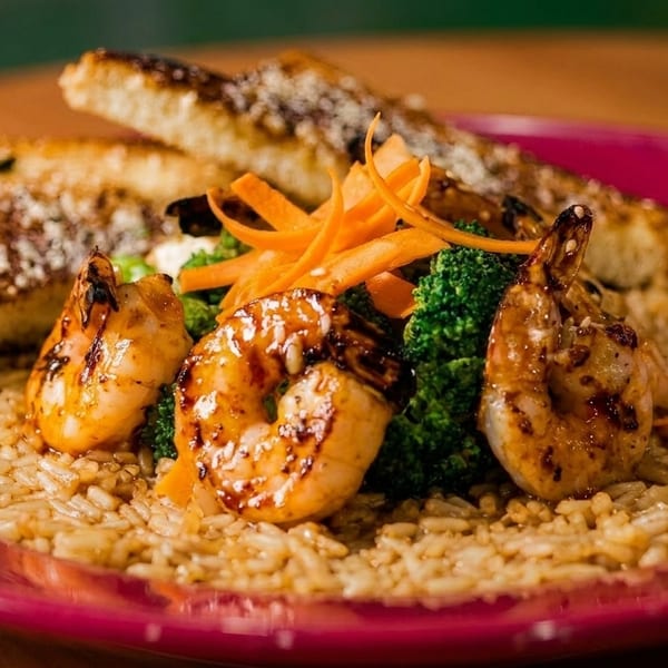 Grilled shrimp, broccoli, and carrot slivers on a bed of rice, with two pieces of toast.