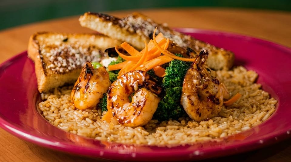 Grilled shrimp, broccoli, and carrot slivers on a bed of rice, with two pieces of toast.